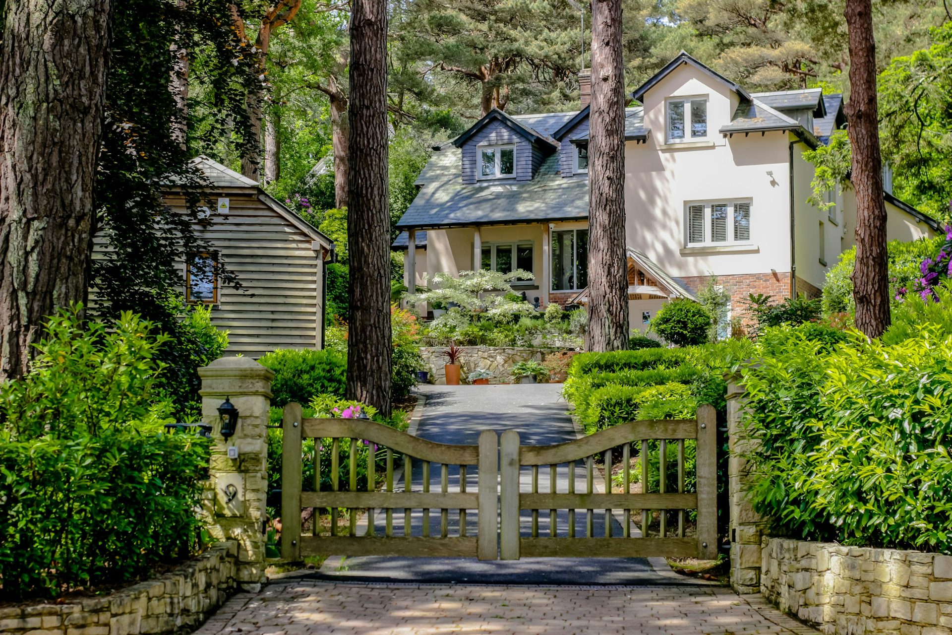 driveway-gate Wood driveway gate between stone posts at a landscaped residential entrance