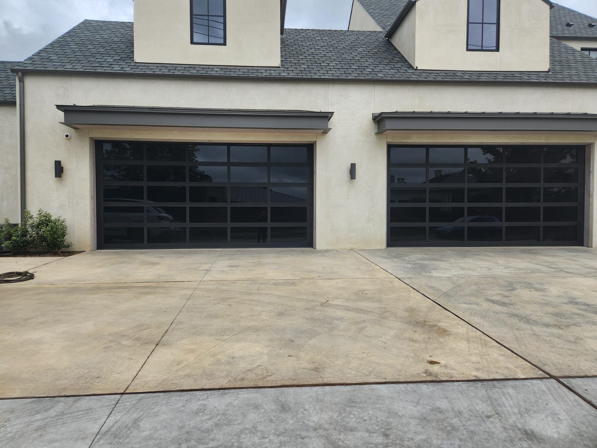 Two black glass garage doors on a stucco home